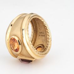 This is part of Chairish’s Fine Jewelry assortment.  Estate David Yurman Renaissance ring crafted in 18 karat yellow.    The out of production David Yurman ring is set with a center set Rhodolite garnet measuring 6mm. Two citrines measure 7mm x 5.5mm. The gemstones are in very good condition and free of cracks or chips. Weighing a hefty 16.6 grams the ring makes a great statement on the hand. The ring has a medium rise (6.5mm - 0.25 inches).  The ring is in very good condition and was recently l Luxury Yellow Sapphire Multi-stone Ring, Luxury Yellow Gold Ring Gemstone, Luxury Yellow Gold Amethyst Ring With Bezel Setting, Luxury Yellow Sapphire Ring With Center Stone, Yellow Gold Jewelry With Gemstone In Wide Band, Yellow Gold Wide Band Jewelry With Gemstone, Yellow Gold Rings With Bezel Setting And Wide Band, Yellow Gold Ring With Yellow Sapphire Center Stone, Yellow Gold Yellow Sapphire Ring With Center Stone