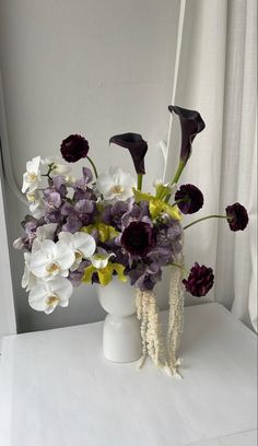 a white vase filled with purple and white flowers