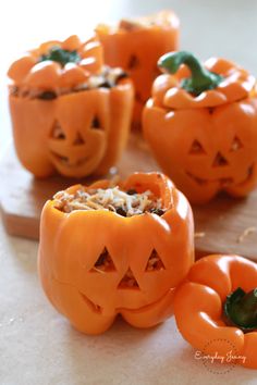 four carved pumpkins sitting on top of a cutting board