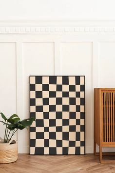 a black and white checkered board next to a potted plant on the floor