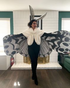 a woman standing in front of a fire place wearing a costume with wings and horns