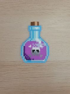 a pixelated bottle with a purple liquid inside sitting on a wooden table next to a pen