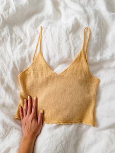 a woman's hand is touching the bottom of a yellow knitted bralet