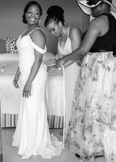 two women in white dresses standing next to each other and one is cutting the ribbon