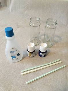 three jars, one with toothbrushes and two empty glass bottles next to them