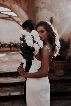 a woman in a white dress holding flowers