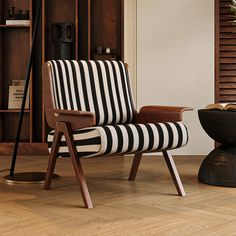 a black and white striped chair sitting on top of a hard wood floor next to a book shelf