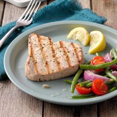 a plate with meat, green beans and tomatoes on it next to a knife and fork