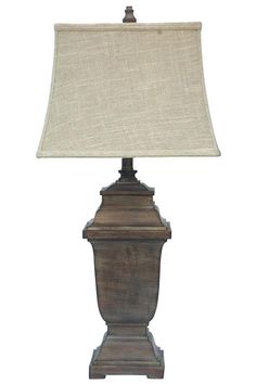 a lamp that is sitting on top of a wooden stand with a white shade over it