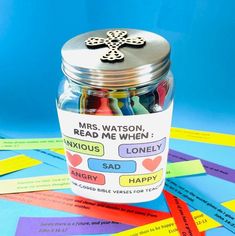 a jar filled with lots of different colored paper strips and a cross on the lid