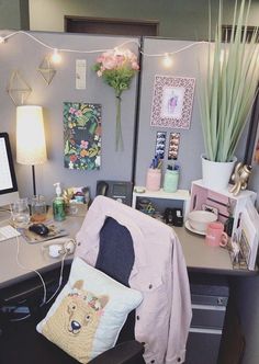 a desk with a chair, computer and flowers on the wall behind it in an office cubicle