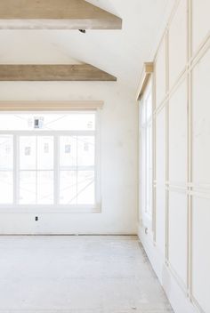 an empty room with white walls and windows