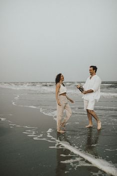 a man and woman are walking on the beach