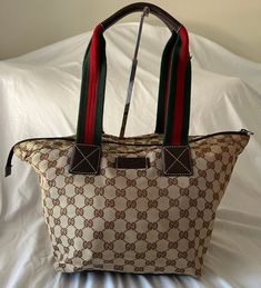 This is an authentic GUCCI Monogram Small Web Handle Tote in Dark Brown. This stylish tote bag is crafted of classic brown on beige Gucci GG monogram canvas. The bag features red and green web stripe handles and a dark brown leather base. The top zipper opens to a spacious brown fabric interior with zipper and patch pockets. It's in excellent condition! Only flaw is that it's missing the leather zipper pull which doesn't affect the ability to use the zipper at all. Base length: 9.00 in Longest length : 15.00 in Height:10.00 in Width: 7.50 in Drop: 8.50 in All measurements are approximate Designer Brown Bag With Canvas Lining, Green Web, Stylish Tote Bag, Gg Monogram, Gucci Monogram, Classic Brown, Brown Fabric, Leather Zipper, Dark Brown Leather