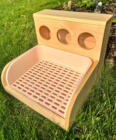 a wooden bench sitting in the grass with three holes on it's seat cover