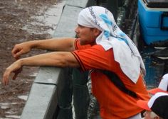 a baseball player leaning on the dugout with his arm out to catch a ball