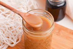 a jar filled with honey sitting on top of a cutting board next to a wooden spoon