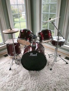 a red drum set sitting on top of a white rug in front of a window