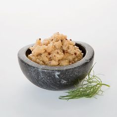 a bowl filled with food sitting on top of a white table next to a sprig of grass