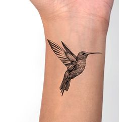 a hummingbird tattoo on the wrist is shown in black and white, with an orange beak