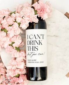 a bottle of wine sitting on top of a table next to some pink carnations