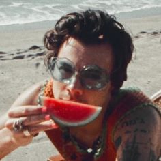 a woman sitting on top of a chair eating a piece of watermelon in front of her face