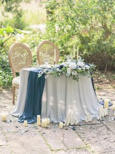 the table is set up with candles and flowers for an elegant wedding reception in the woods