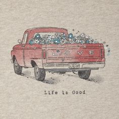 an old red truck with flowers in the back and words written on the side that read love life is good