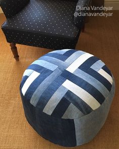 a blue and white round ottoman sitting on top of a wooden floor next to a black chair