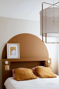 a bed that has some pillows on it and a lamp in the corner next to it