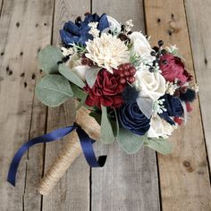 a bridal bouquet with red, white and blue flowers on a wooden table top