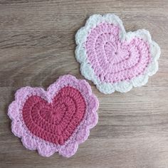 two crocheted heart coasters sitting on top of a wooden table next to each other