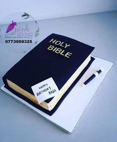 a cake made to look like a bible with a pen on it and a name tag