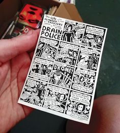 a person holding up a piece of paper with comic strips on it