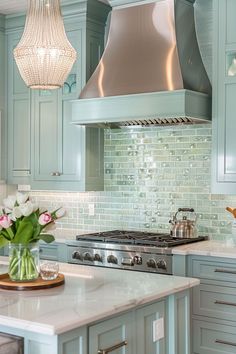 a kitchen with blue cabinets and an island in front of a stove top oven that has a hood over it