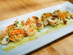 a white plate topped with shrimp and broccoli on top of a wooden table