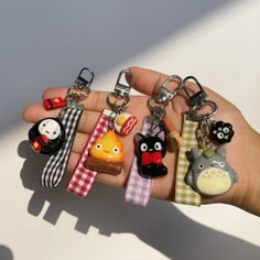 a hand holding several different key chains with animals on them, including cats and pandas