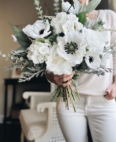 a woman holding a bouquet of white flowers