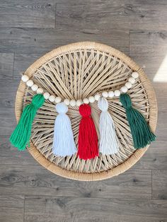 three tassels on a woven wicker basket with white beads and green, red, and white tassels