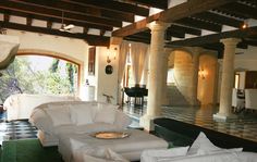 a living room filled with white furniture and lots of windows next to a black and white checkered floor