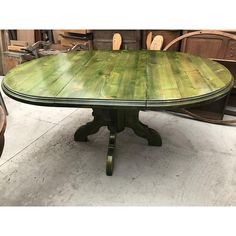 a green table sitting on top of a white floor next to chairs and other furniture