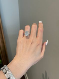 a woman's hand with a diamond ring on her left wrist, in front of a mirror