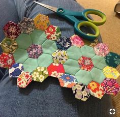 a person sitting on the floor with some scissors and patchwork pieces in front of them