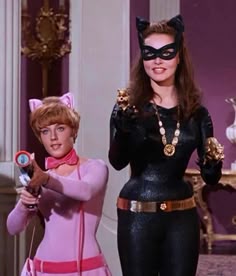 two barbie dolls dressed in cat costumes and one is holding a cell phone to her ear