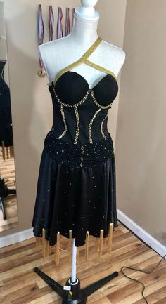 Black and gold rhythm/Latin dress.  Unique neckline and fringe accents on the skirt give this dress eye catching movement.  Flattering corset top with ruched accent on hip line.  Sparkling gold stones add nice contrast to the black.  Fits a size S-M. **I also do custom designs** Fitted Gold Corset For Costume Party, Fitted Black Corset For Dance, Black Embellished Glamorous Corset Dress, Black Embellished Corset Dress For Cocktail, Glamorous Black Embellished Corset Dress, Black Embellished Dress For Costume Party, Black Embellished Fitted Corset, Gold Fitted Dance Dress, Gold Fitted Dress For Dance