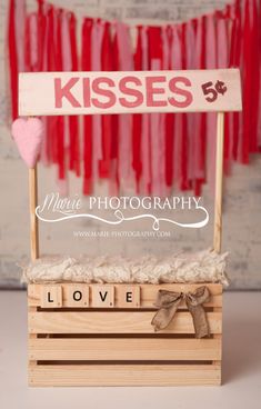 a wooden box with a sign that says kisses on it and a heart hanging from the top