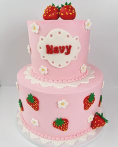 a three layer pink cake with strawberries on top