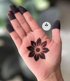 a woman's hand with a flower tattoo on her left palm, and a white sticker in the background