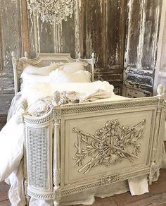 an old fashioned bed with white sheets and pillows