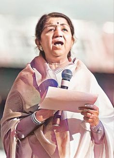 a woman holding a microphone while standing in front of a microphone with her mouth open